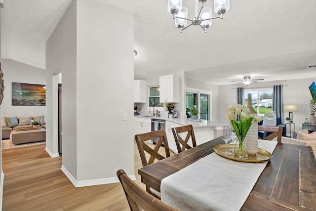 dining room featuring light wood-style floors, lofted ceiling, baseboards, and ceiling fan with notable chandelier