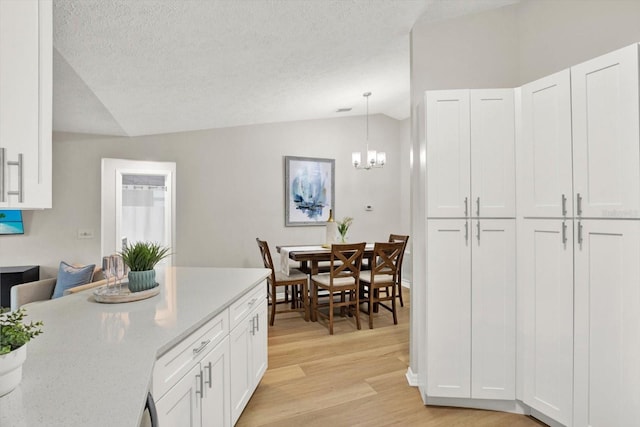 kitchen with white cabinets, vaulted ceiling, and hanging light fixtures