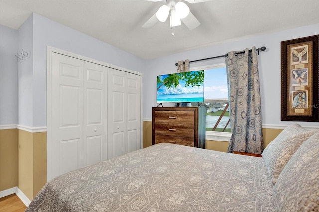 bedroom featuring ceiling fan, a closet, wood finished floors, and baseboards