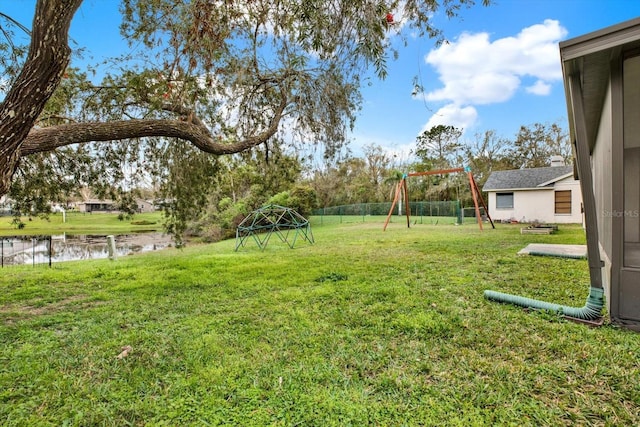 view of yard with a water view, fence, and a playground