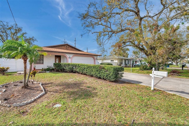 view of front of house with stucco siding, an attached garage, a front yard, fence, and driveway