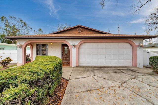 single story home featuring driveway, fence, an attached garage, and stucco siding