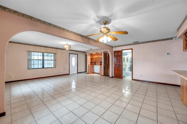 unfurnished room featuring arched walkways, light tile patterned floors, visible vents, a textured ceiling, and baseboards