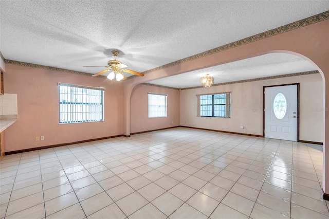 unfurnished room featuring a ceiling fan, a textured ceiling, baseboards, and light tile patterned floors