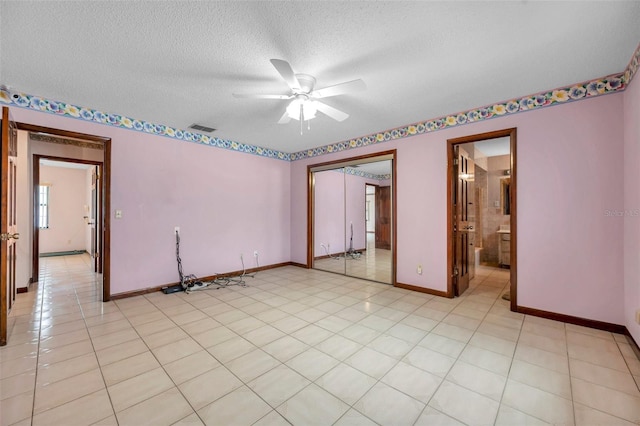 empty room with a ceiling fan, visible vents, a textured ceiling, and baseboards