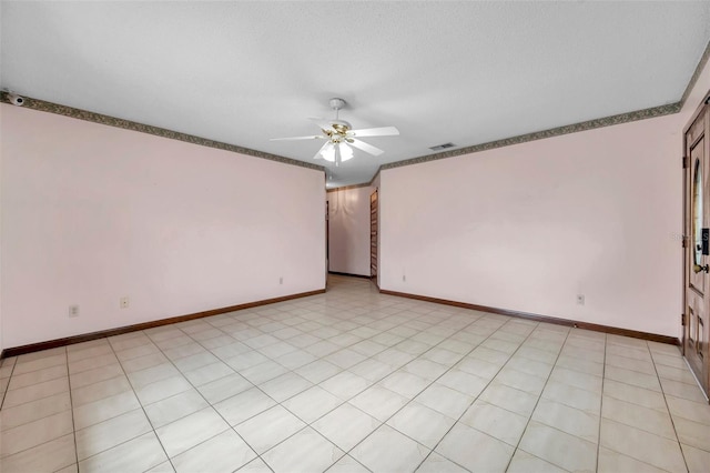 spare room with baseboards, visible vents, ceiling fan, and a textured ceiling