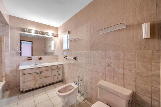 full bathroom with tile patterned flooring, toilet, vanity, tile walls, and a bidet