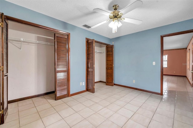 unfurnished bedroom featuring light tile patterned floors, baseboards, visible vents, and multiple closets