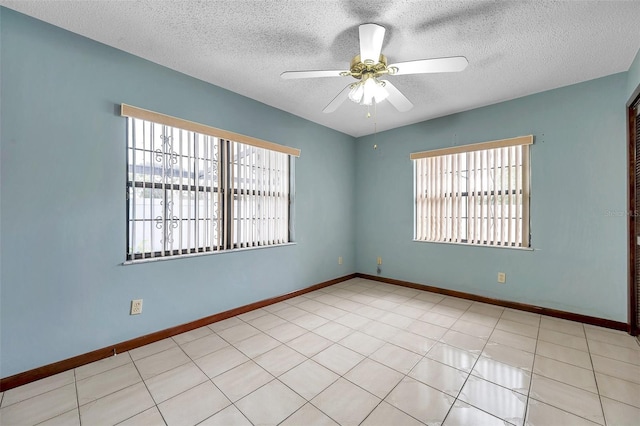 empty room featuring light tile patterned flooring, a ceiling fan, and baseboards