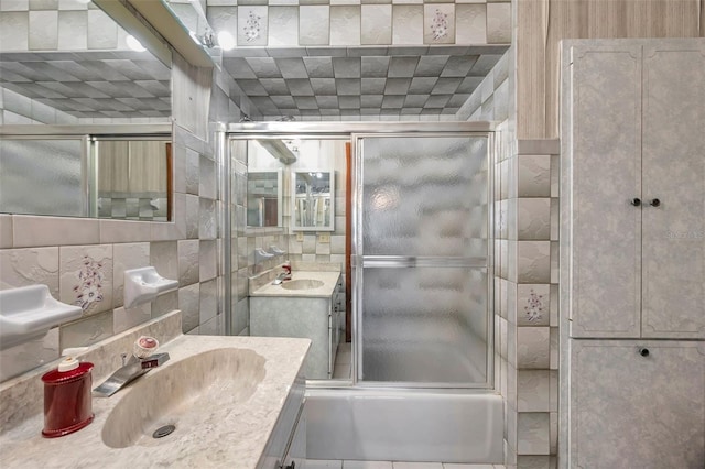 full bathroom with bath / shower combo with glass door, vanity, and decorative backsplash