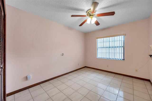 unfurnished room with ceiling fan, a textured ceiling, baseboards, and light tile patterned floors