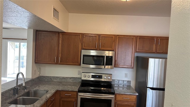 kitchen with visible vents, appliances with stainless steel finishes, brown cabinetry, and a sink