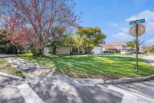 view of front of property featuring a front lawn, an attached garage, and a residential view