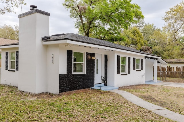 view of front of home with a front yard, a chimney, fence, and stucco siding