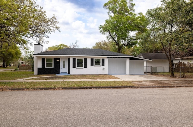 ranch-style home featuring an attached carport, a chimney, fence, and driveway