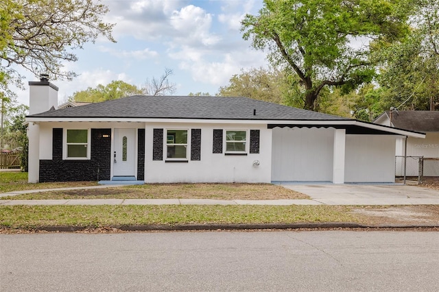 ranch-style house featuring driveway, a chimney, an attached carport, fence, and stucco siding