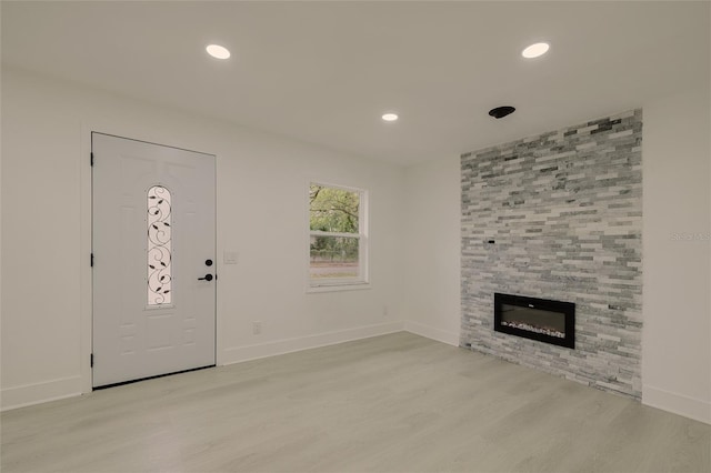 unfurnished living room featuring baseboards, a fireplace, light wood-style flooring, and recessed lighting