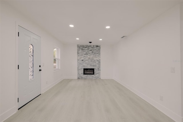 unfurnished living room with recessed lighting, a fireplace, visible vents, baseboards, and light wood-style floors