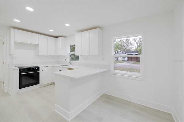 kitchen featuring wall oven, a wealth of natural light, a sink, and a peninsula