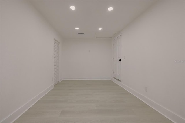 unfurnished room with attic access, visible vents, baseboards, light wood-type flooring, and recessed lighting