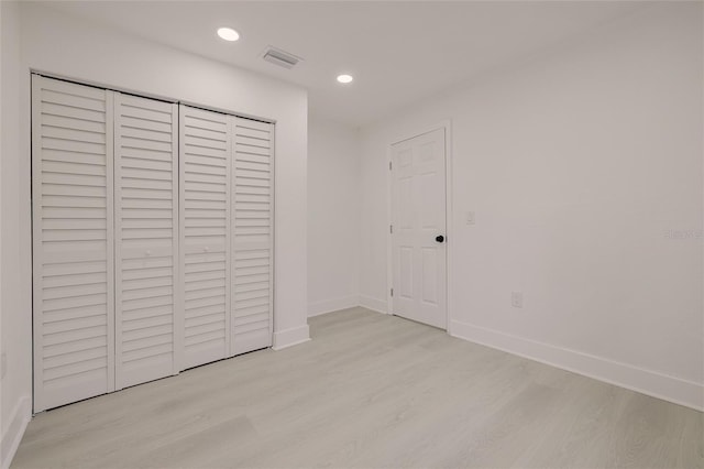 unfurnished bedroom with recessed lighting, a closet, visible vents, wood finished floors, and baseboards