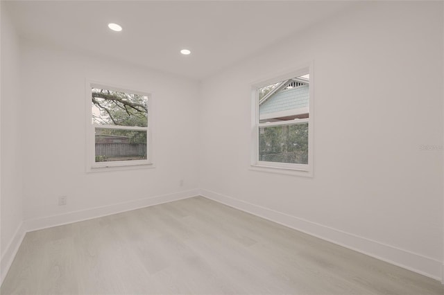 spare room featuring a wealth of natural light, light wood finished floors, and baseboards