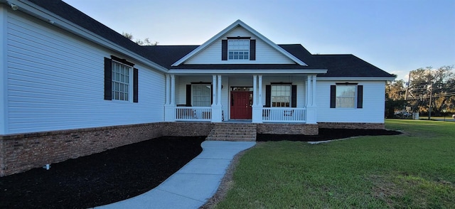 view of front of home featuring a porch, a front lawn, and brick siding