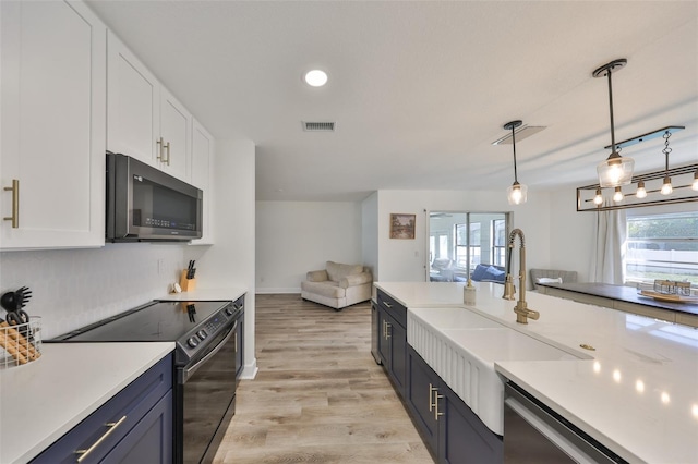 kitchen with appliances with stainless steel finishes, pendant lighting, light countertops, and visible vents