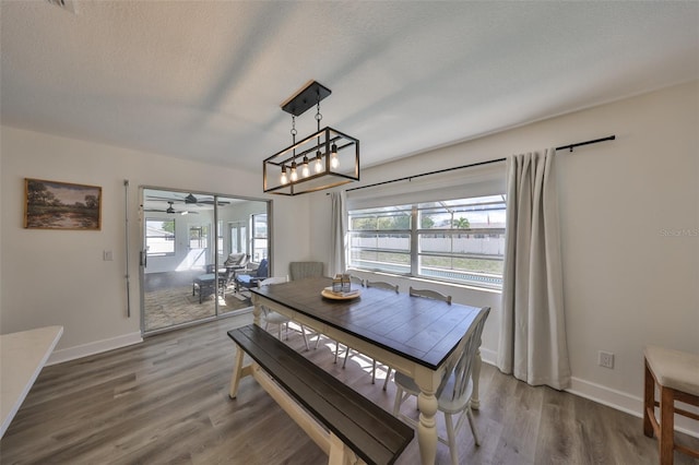 dining area featuring a textured ceiling, wood finished floors, and baseboards