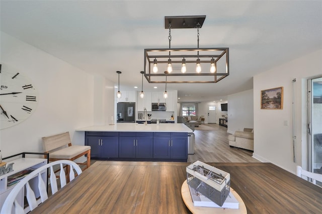 6333 Spanish Main Dr, Apollo Beach, FL 33572 - kitchen with stainless steel microwave, open floor plan, light countertops, black refrigerator with ice dispenser, and pendant lighting