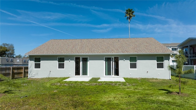 back of property with a yard, fence, and stucco siding