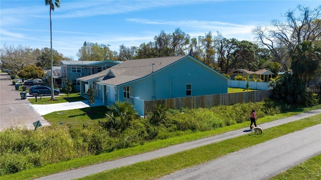 view of side of home featuring driveway, fence, and stucco siding