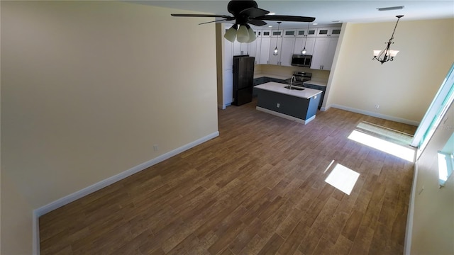 kitchen featuring dark wood-style floors, stainless steel microwave, freestanding refrigerator, open floor plan, and a sink