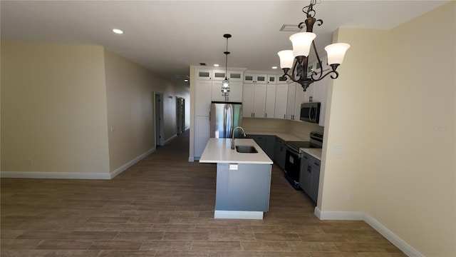 kitchen with an island with sink, wood finished floors, stainless steel appliances, light countertops, and a sink