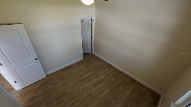 spare room featuring baseboards and wood finished floors