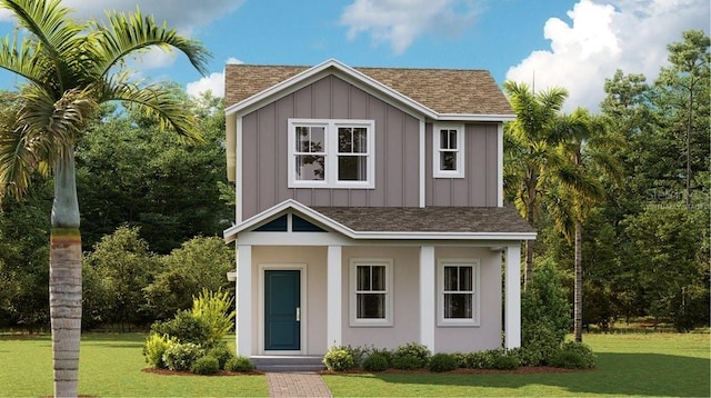 view of front facade with board and batten siding, a front yard, and roof with shingles