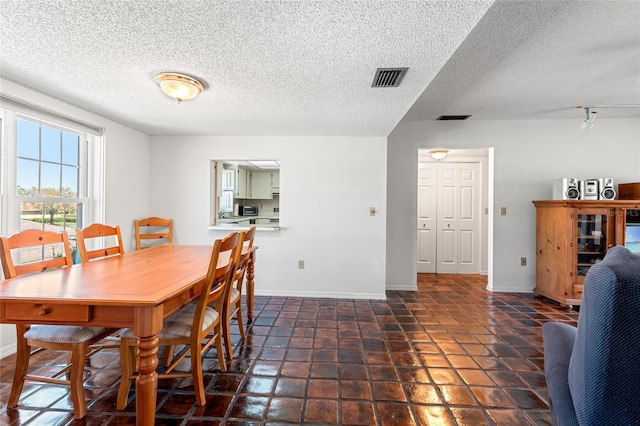 dining room with a textured ceiling, visible vents, and baseboards