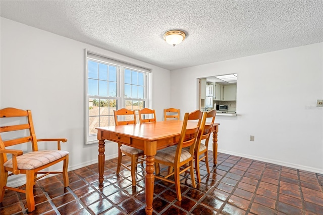 dining space with baseboards and a textured ceiling