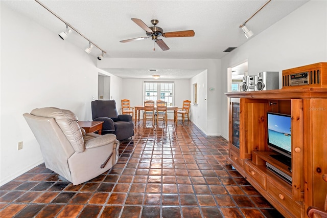 living room with a ceiling fan, baseboards, visible vents, and a textured ceiling