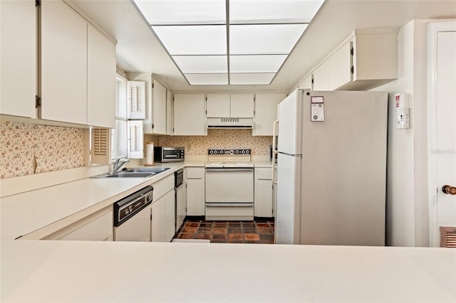 kitchen featuring under cabinet range hood, white appliances, a sink, white cabinetry, and light countertops