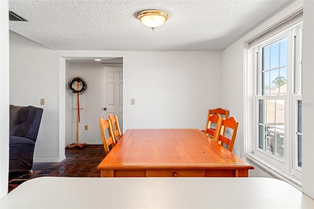 dining room featuring a textured ceiling and baseboards