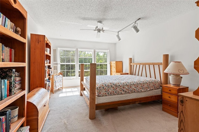 bedroom with light carpet, ceiling fan, a textured ceiling, and track lighting