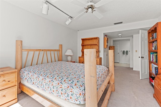 bedroom with visible vents, light carpet, a textured ceiling, and rail lighting