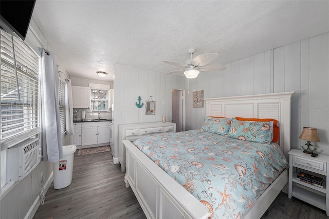 bedroom featuring a ceiling fan, wood finished floors, a textured ceiling, cooling unit, and a sink