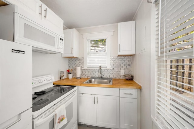 kitchen with white appliances, butcher block counters, a sink, white cabinets, and decorative backsplash