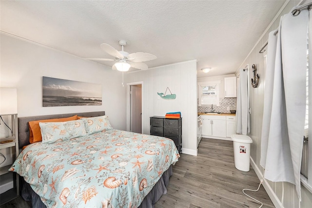 bedroom with ensuite bath, ceiling fan, wood finished floors, a textured ceiling, and a sink