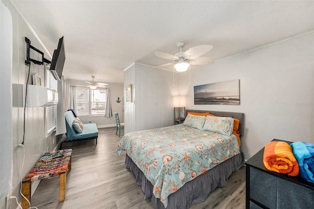 bedroom with ceiling fan, a textured ceiling, baseboards, and wood finished floors