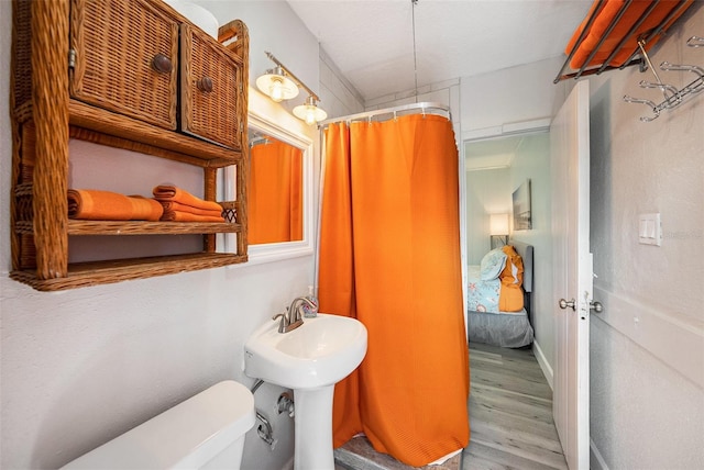 full bathroom with toilet, a shower with curtain, and wood finished floors