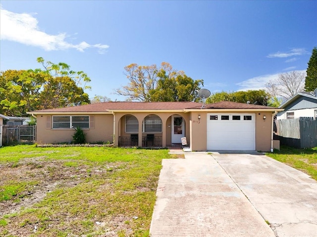 ranch-style home with an attached garage, fence, a front lawn, and stucco siding