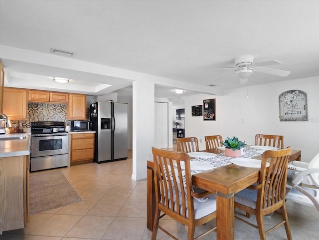 dining room with ceiling fan, light tile patterned flooring, a raised ceiling, and visible vents